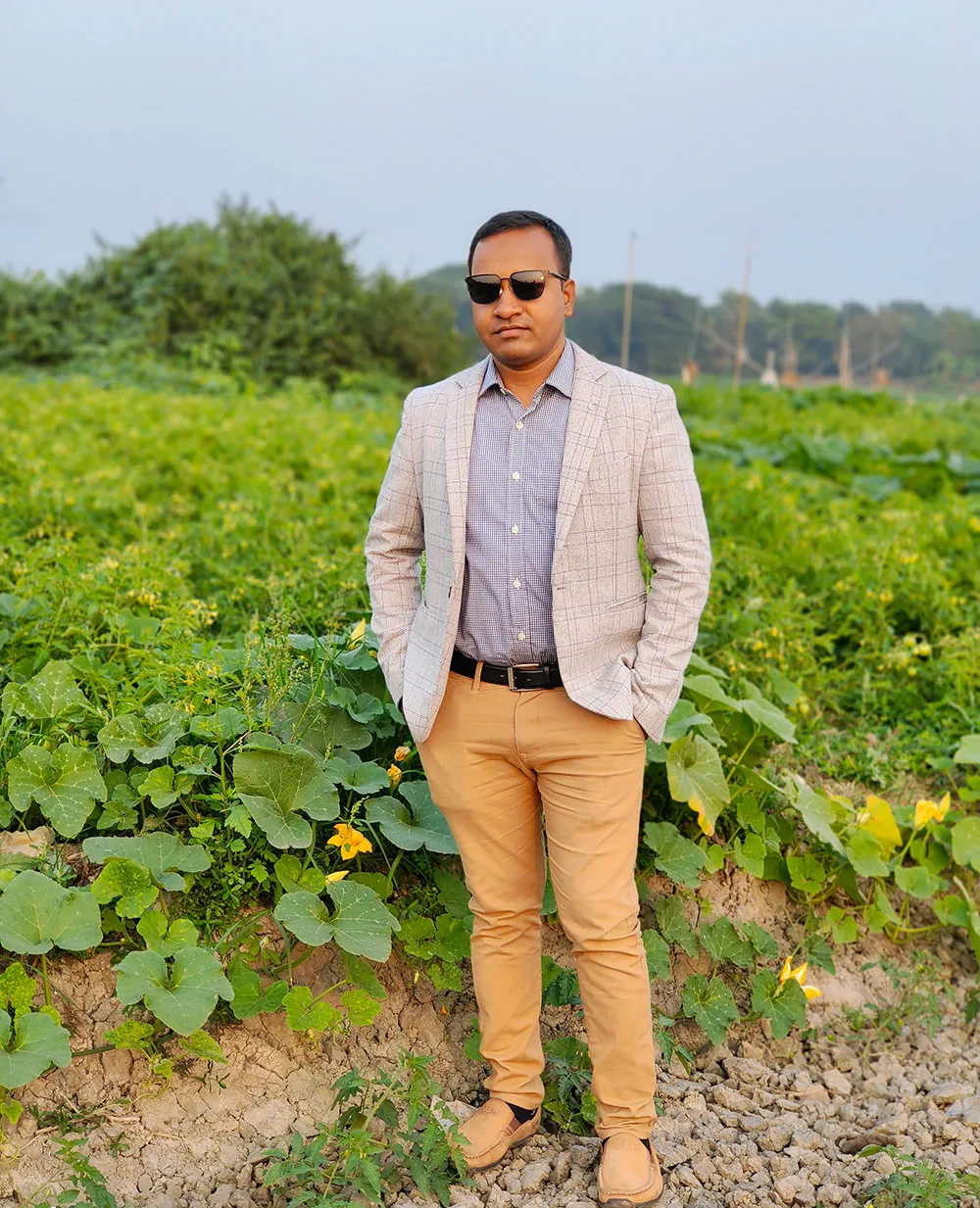 Engineer Khokon standing in a green vegetable field in his village, Purbachal, Bangladesh
